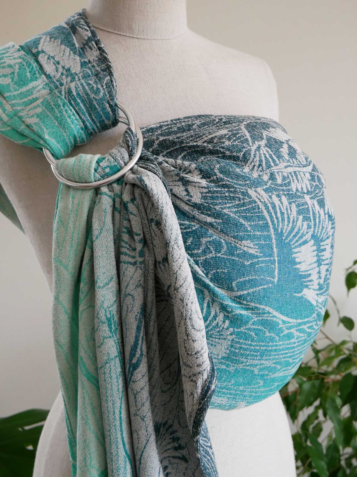 Mannequin wearing a tealpatterned sling with a ring, against a neutral background.