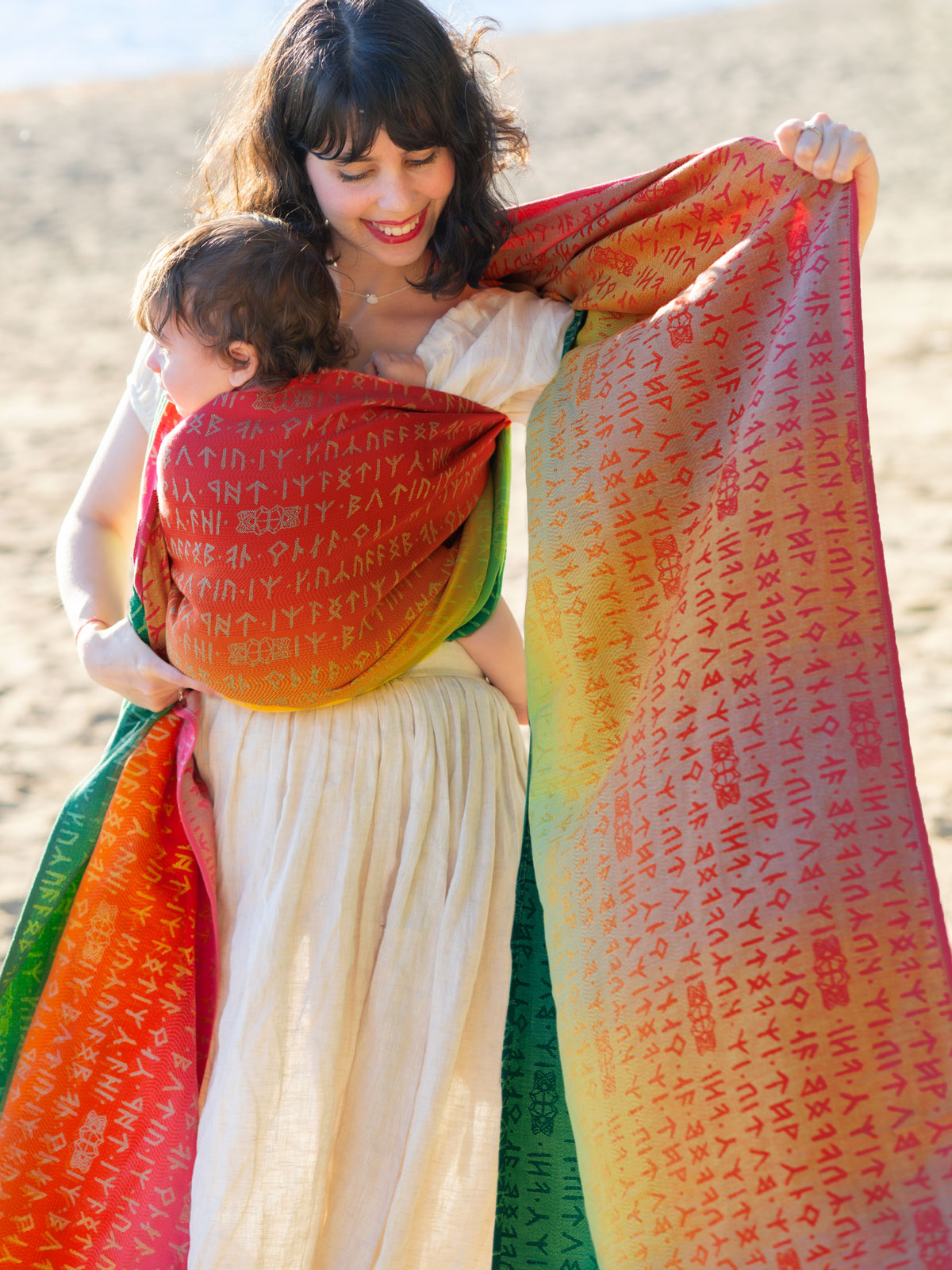 Woman holding a child with a colourful woven wrap