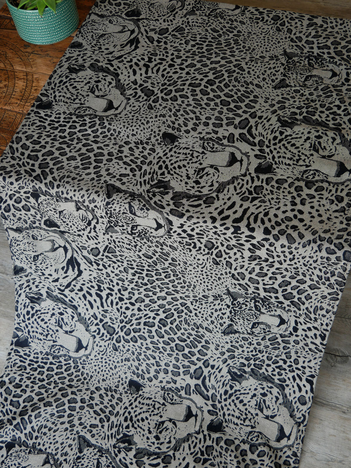 Leopard print fabric on a wooden surface with a plant in the corner.