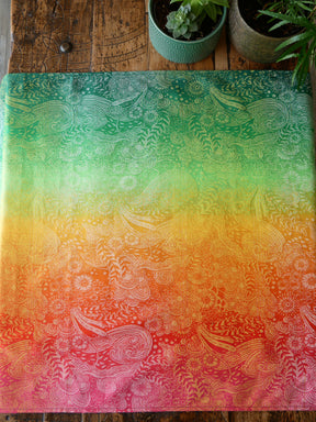 Colourful patterned Marina Starburst Baby Wrap on a wooden surface with plants.